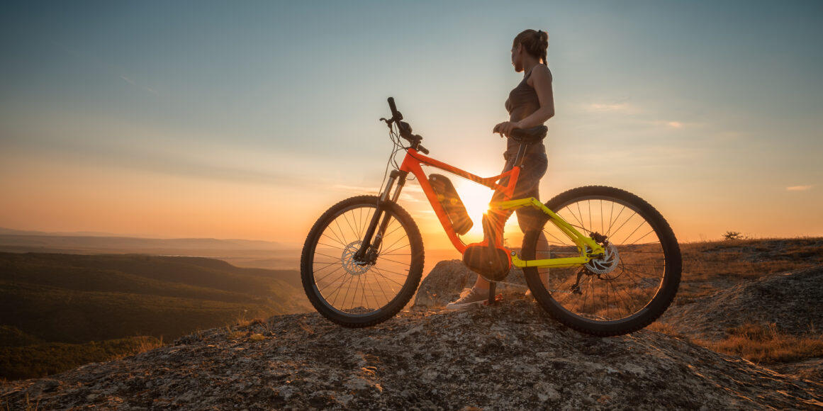 VTT électrique au sommet d’une montagne au coucher de soleil, rider en contemplation avec un VTTAE sur un point de vue panoramique
