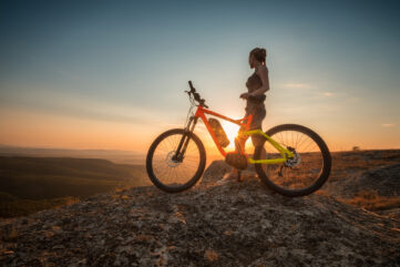 VTT électrique au sommet d’une montagne au coucher de soleil, rider en contemplation avec un VTTAE sur un point de vue panoramique