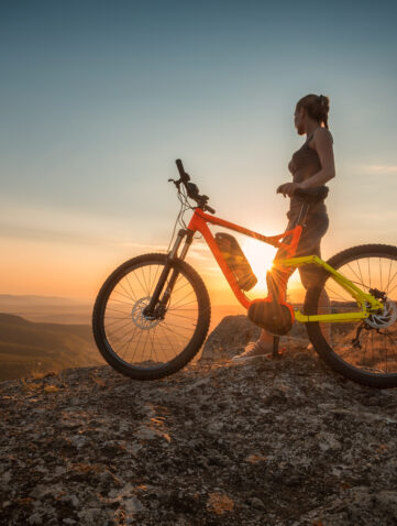 VTT électrique au sommet d’une montagne au coucher de soleil, rider en contemplation avec un VTTAE sur un point de vue panoramique